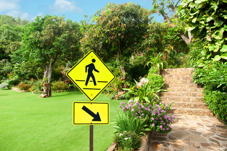 Pedestrian sign with a person walking on yellow against nice stone landscaping pathway