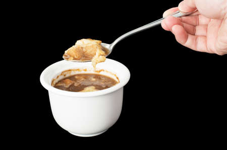 Hand holding spoon with cheese on onion soup isolated on black backgroundの写真素材