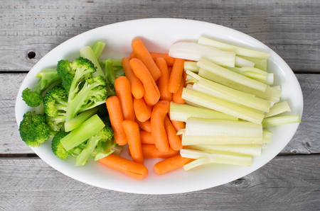 Vegetable tray with celery, broccoli, carrots on a wooden tableの写真素材