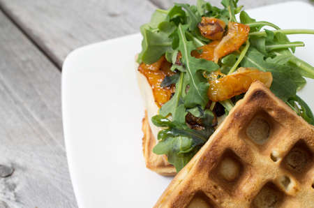 Homemade waffle burger on a white ceramic plate against wooden backgroundの写真素材