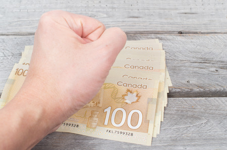 Hand pounding on a stack of bank notes on a wooden tableの写真素材