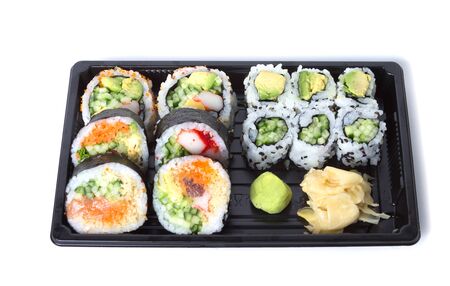 Assorted sushi rolls in a black plastic tray against white backgroundの写真素材