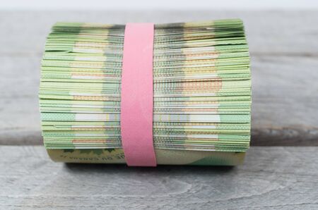 Roll of money on wooden tableの写真素材