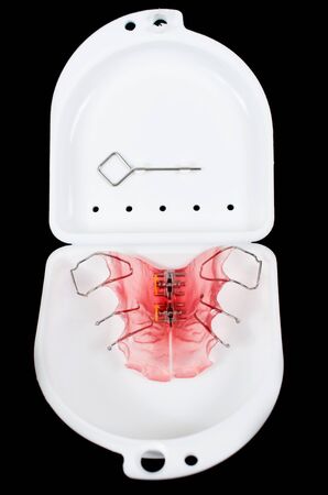 Teeth retainer in a white plastic container isolated on black backgroundの写真素材