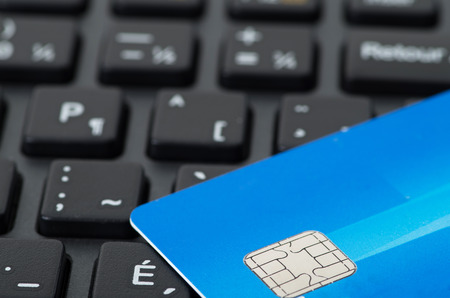 Blue credit card on black keyboard closeup studio shot