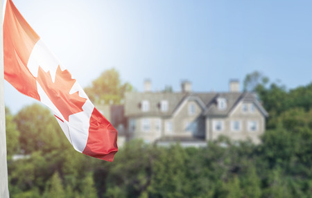Canadian flag waving over 24 Sussex drive in blurred background with flare effect applied