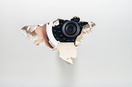 Hand holding security behind a cracked drywall, domestic spying conceptの写真素材