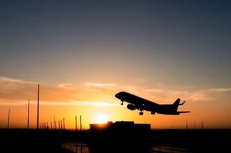 Commercial airplane taking off during sunset over a marinaの写真素材