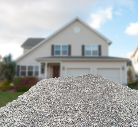 Big pile of crushed stones in front of a finished house in blurred background, construction conceptの写真素材
