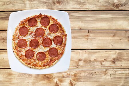 Pepperoni and cheese pizza on a wooden background with retro lookの写真素材
