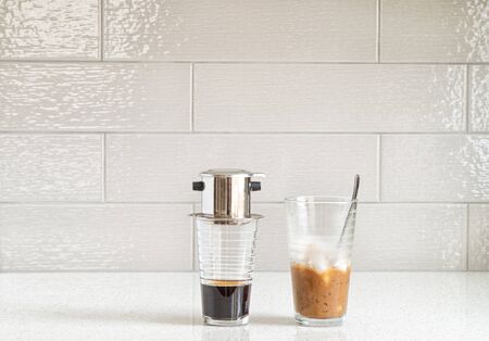 Vietnamese iced coffee with condensed milk, cafe sua da on granite counter top against a ceramic backsplashの写真素材