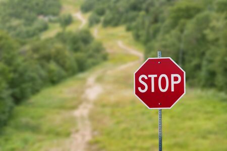 Stop sign against green forest trail backgroundの写真素材