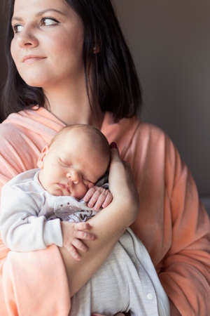 a young mother enjoys the first days of motherhood with her child holding it in her armsの写真素材