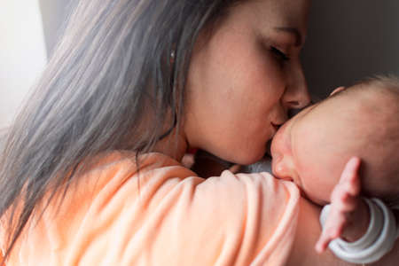 a young mother enjoys the first days of motherhood with her child loving him and holding him in her armsの写真素材