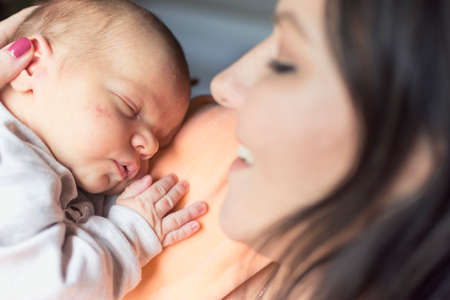a young mother enjoys the first days of motherhood with her child holding it in her arms
