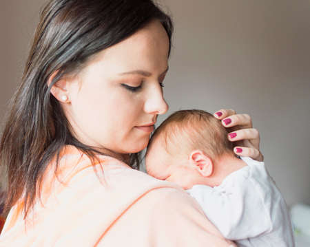 a young mother enjoys the first days of motherhood with her child holding it in her arms