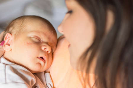 A young mother enjoys the first days of motherhood with her child holding it in her arms