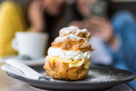 close up of a princess donut on a plate and two blurred people in the backgroundの写真素材