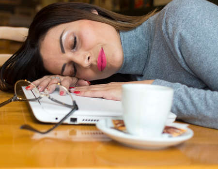 a very tired business woman sleeping on a laptop computerの写真素材