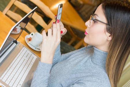 businesswoman using a mobile phone while on a break in her favorite cafeteria