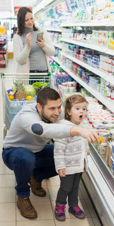 young family buying food in supermarket,mother calculating on smartphoneの写真素材