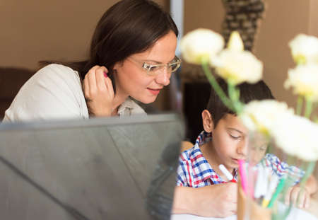 The mother and son sit at the table and paint together. The mother helps her son to choose the...