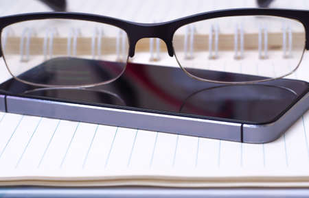 On the open book glasses and smartphoneの写真素材