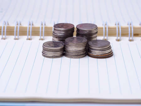Stack of coins on a  book on a wooden desk.Concept of saving moneyの写真素材