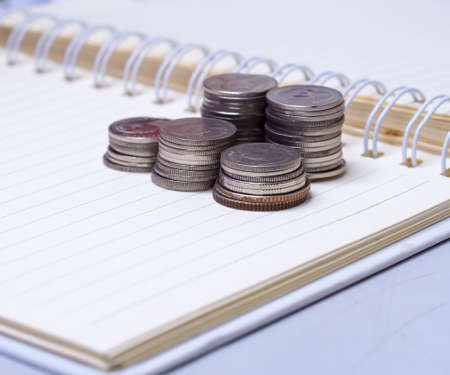 Stack of coins on a  book on a wooden desk.Concept of saving moneyの写真素材