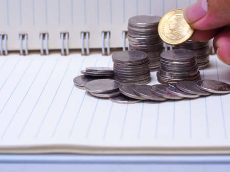 Stack of coins on a  book on a wooden desk.Concept of saving moneyの写真素材