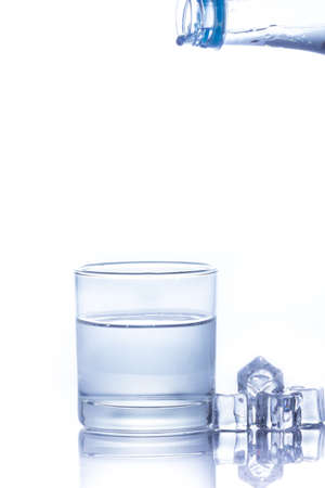 Water is poured into a glass with ice cubes