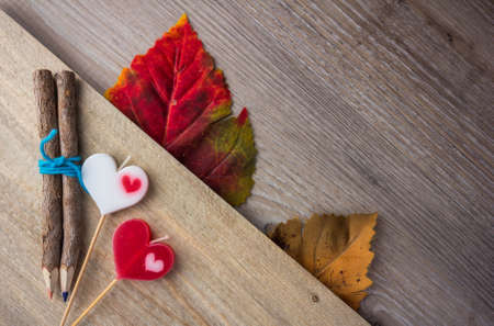 pencil and heart-shaped candle placed on wood.の写真素材