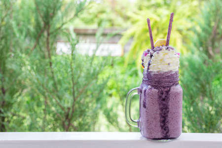 sweet blueberry milkshake drink on green nature bokeh at coffee shopの写真素材