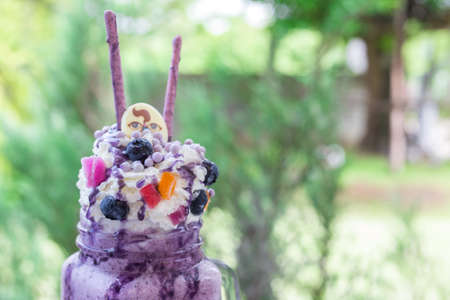 sweet blueberry milkshake drink on green nature bokeh at coffee shopの写真素材