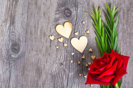 Heart shape with green foliage and red rose flower on wood texture background, Studio shot on wooden background.の写真素材