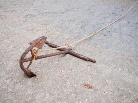 Anchor and white rope on the sand.