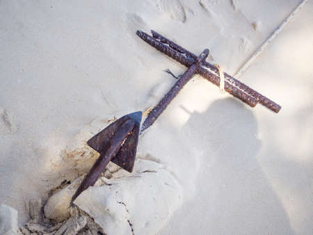 Anchor and white rope on the sand.