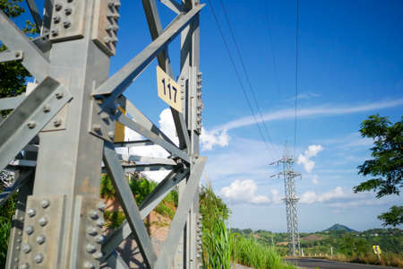 High voltage pole on blue sky background.