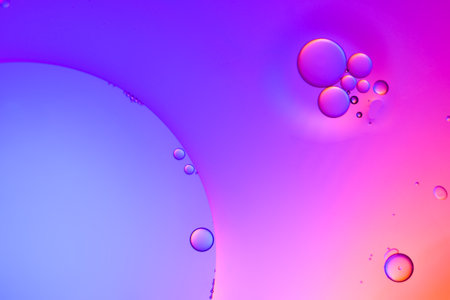 Top view movement of oil bubbles in the liquid. Oil surface multicolored background. Fantastic...