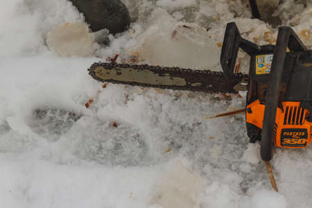 Chainsaw lying in the snow on frozen lakeの写真素材