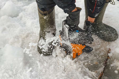 Man cutting chainsaw shell in ice, winter fishing, weather, saviorの写真素材