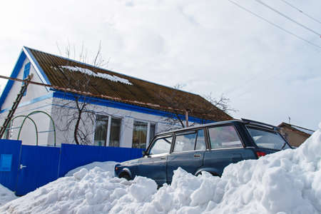 Old village house and a car in the snow Sunny winter dayの写真素材