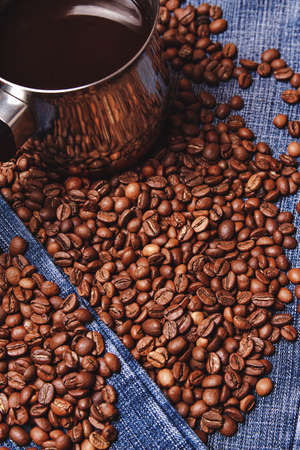 Old cezve and black coffee beans on jeans backgroundの写真素材
