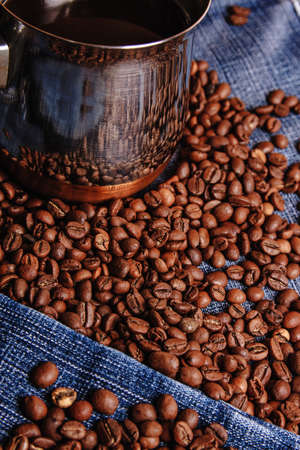 Old cezve and black coffee beans on jeans backgroundの写真素材