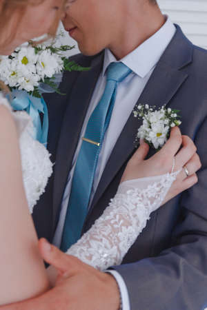 brides hands pinning boutonniere to groom jacketの写真素材