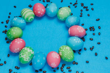 Frame of hand painted pastel Easter eggs over a blue background