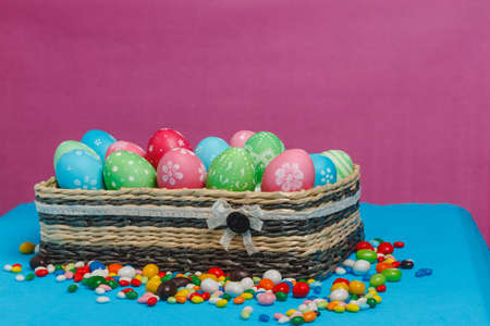 Colored Easter eggs in a basket on a blue-pink background. Easter background. Easter eggs.