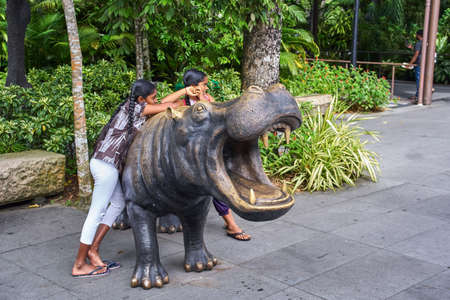 SINGAPORE - NOBEMBER 29, 2017: Children on bronze hippo near zoo entranceのeditorial素材