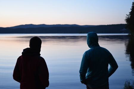 Two men look at a lake. Sunrise.の写真素材