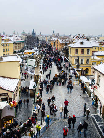 PRAGUE, CZECH REPUBLIC, JANUARY 30, 2015: people are walking from the charles bridge towards prague castle in prague, whose rooftops are covered by snow.のeditorial素材